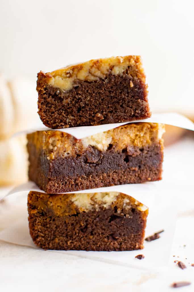 Three pumpkin brownies stacked with parchment paper.