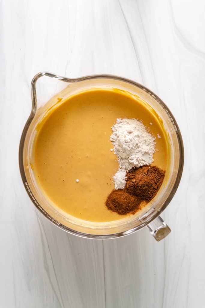 Flour and spices in a bowl with pumpkin cheesecake filling.