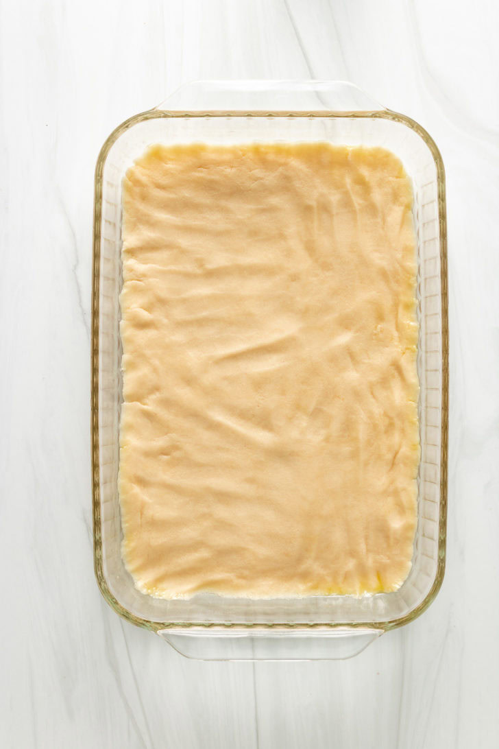 Top down view of unbaked shortbread crust in a baking dish.