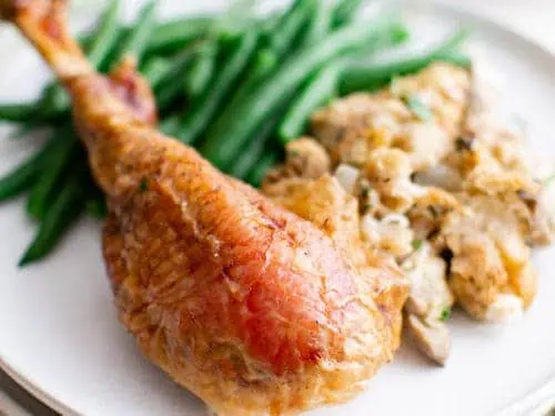 Roast turkey leg with green beans on a plate.