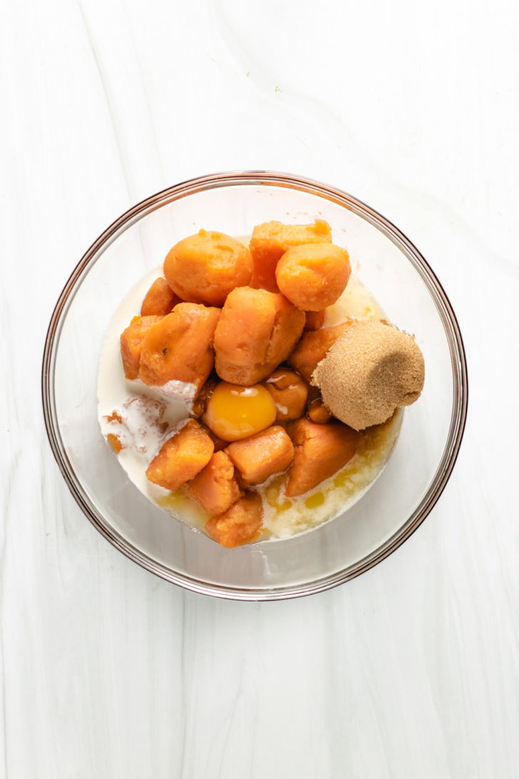Ingredients for sweet potato casserole in a glass bowl.