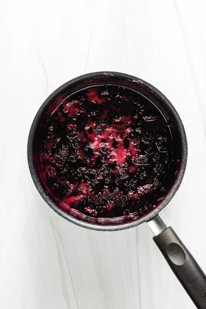 Blackberries, sugar, and water cooking in a pan.