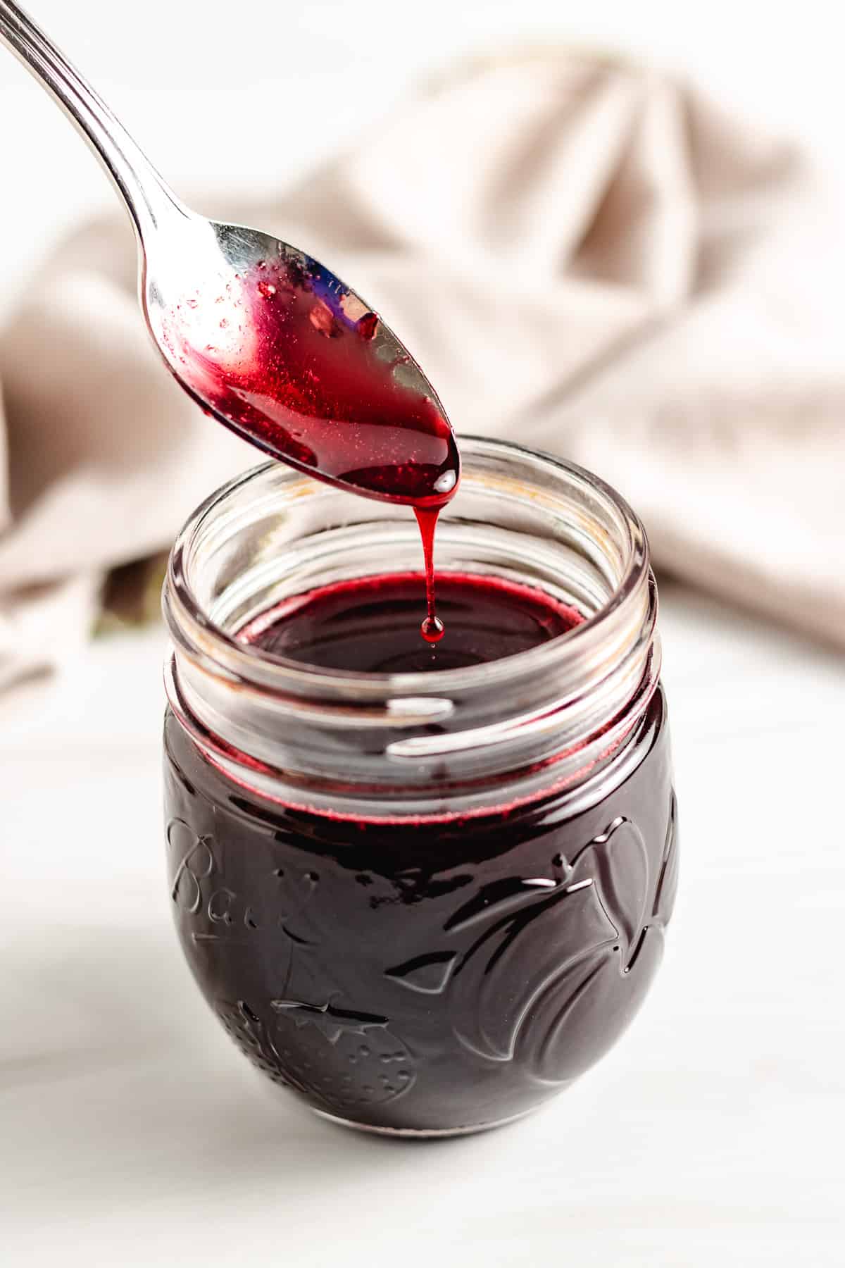 Spoon being dipped into blackberry syrup.
