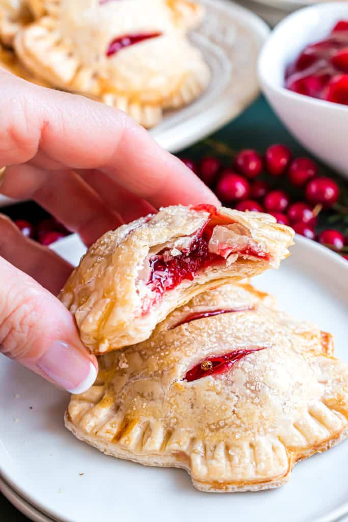 Hand setting a cherry hand pie on a plate.