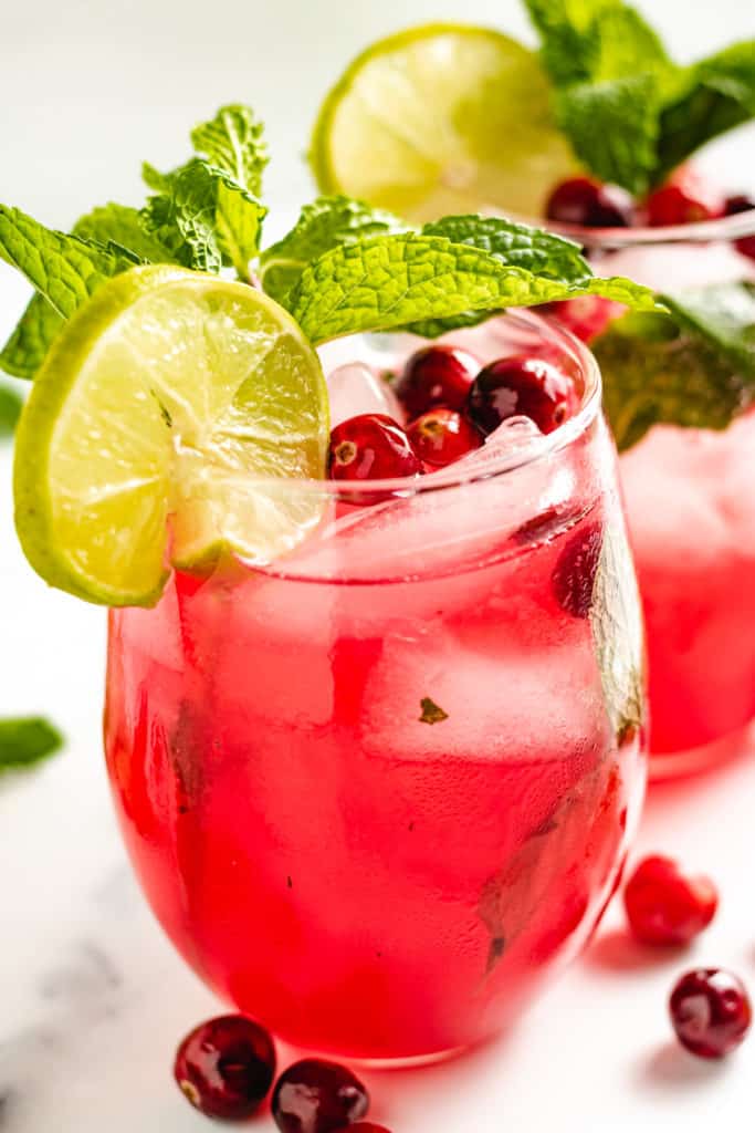 Close up view of two cranberry mojitos with lime slices and fresh mint.