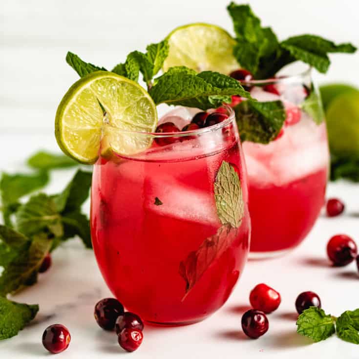 Cranberry mojitos garnished with limes and mint.