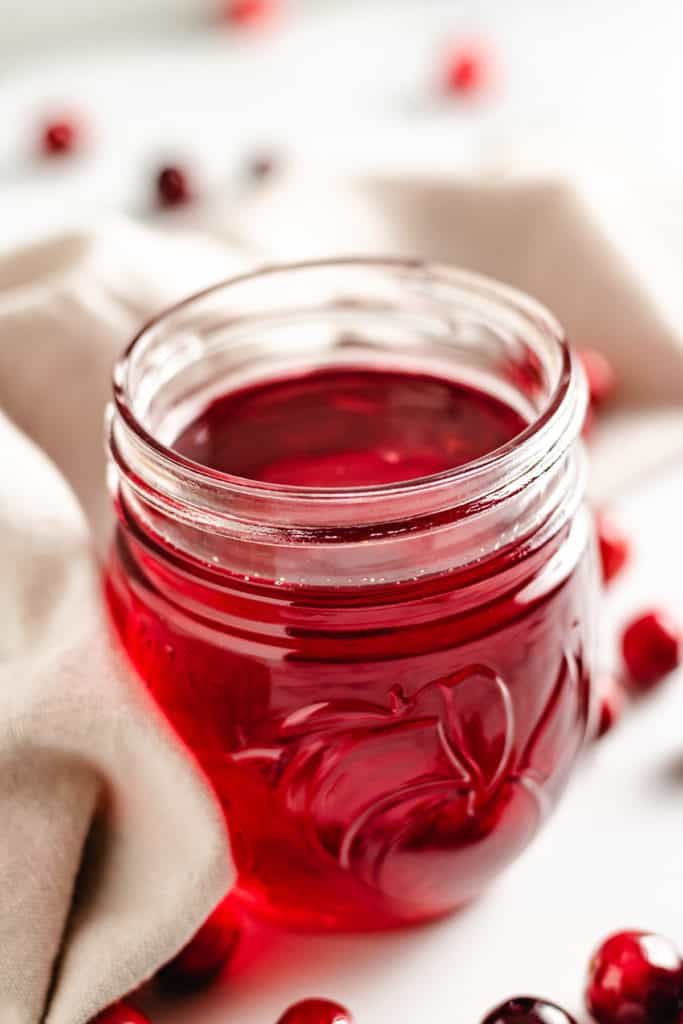 Close up view of cranberry simple syrup in a mason jar.