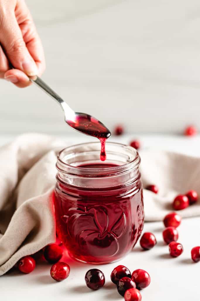 Cranberry simple syrup on a spoon.