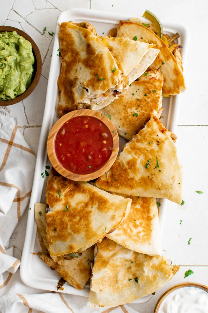 Fajita quesadillas on a platter with salsa.