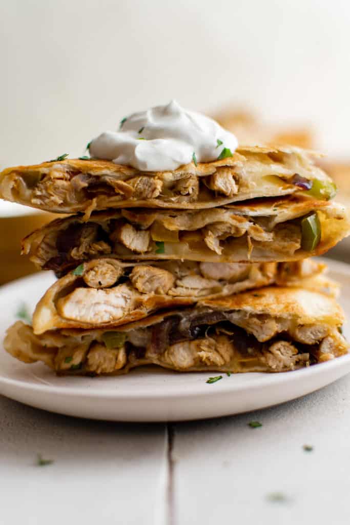 Stack of fajita quesadillas with sour cream.