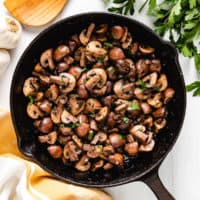 Top down view of sauteed mushrooms in a pan.