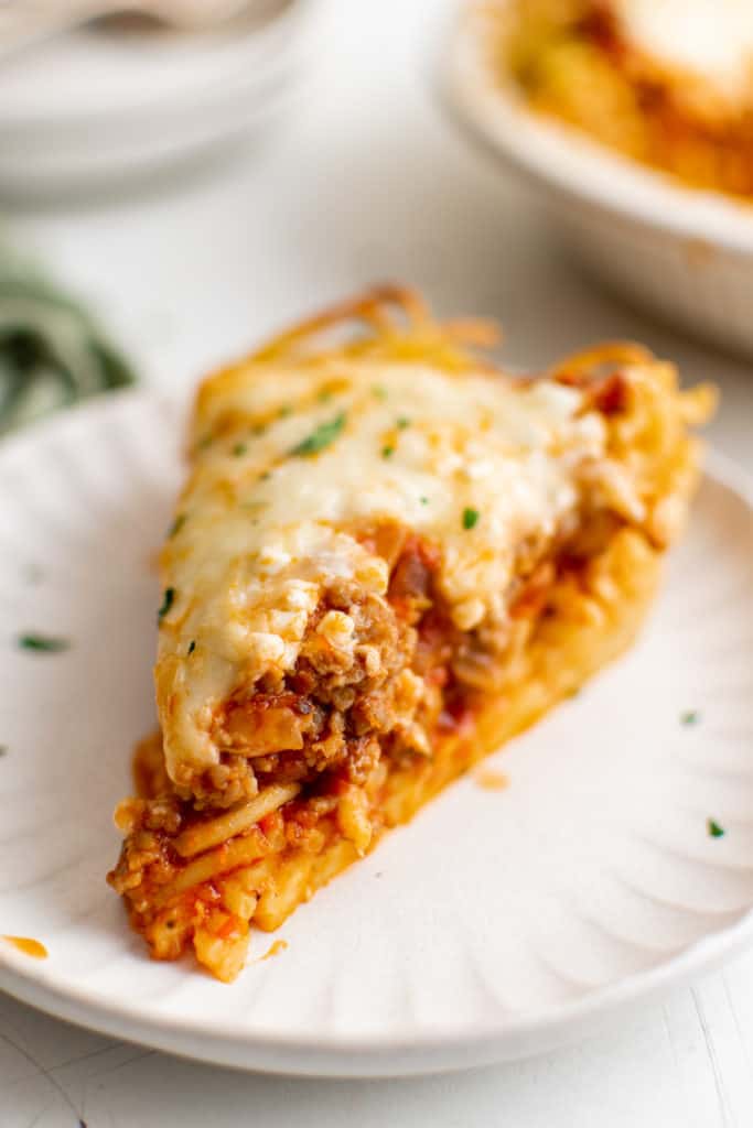 Slice of spaghetti pie topped with mozzarella cheese.