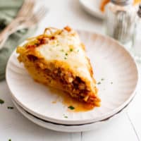 White plate holding a piece of spaghetti pie.