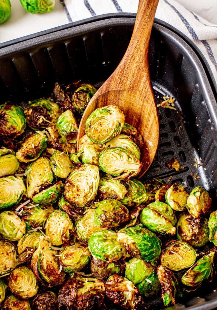 Spatula scooping brussel sprouts out of an air fryer.