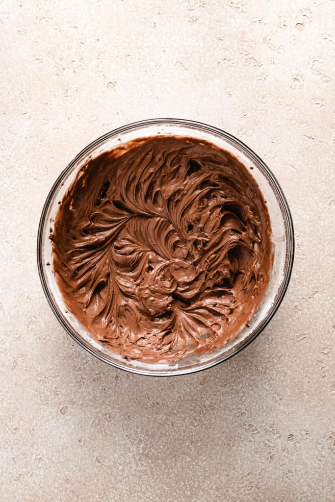 Chocolate frosting in a glass bowl.