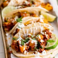 Platter of chorizo tacos drizzle with Mexican crema.