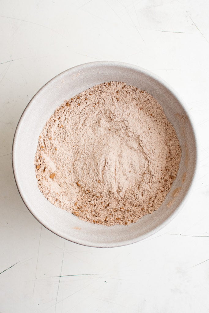 Flour, sugar, cocoa powder, baking powder, baking soda, and salt whisked together in a bowl.