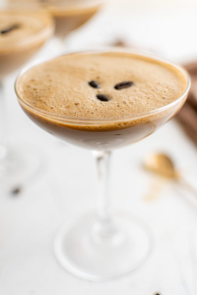 Three coffee beans on top of an espresso martini.