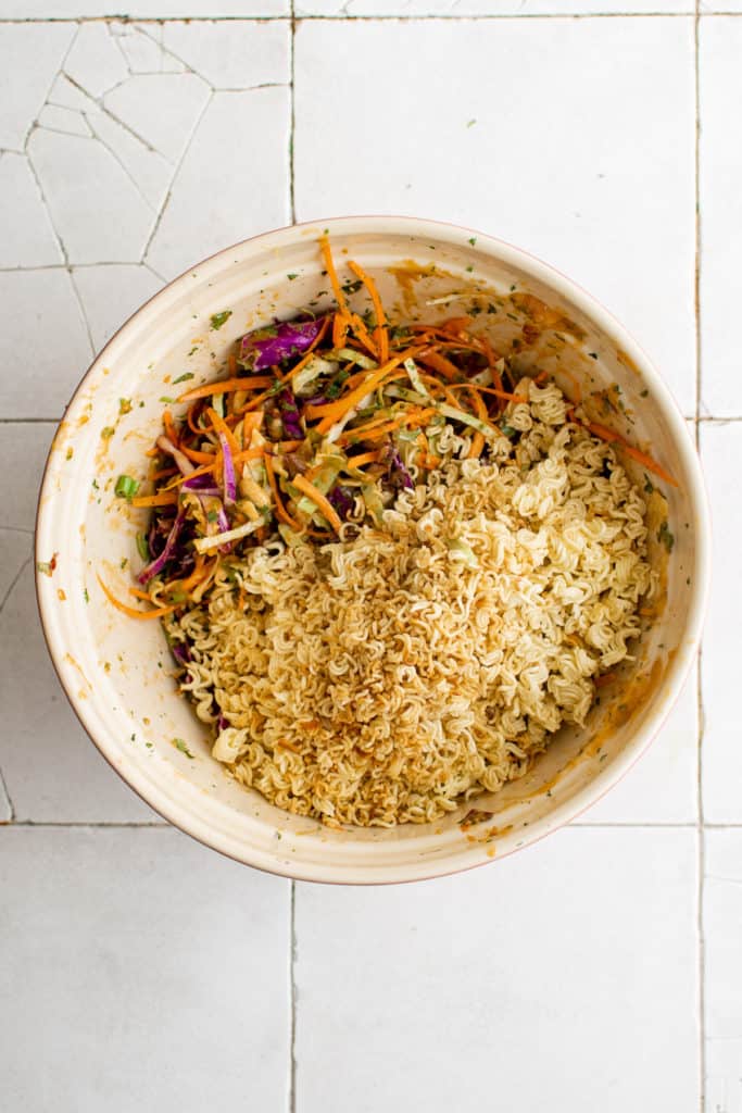 Top down view of ramen noodles on top of salad mix in a bowl.