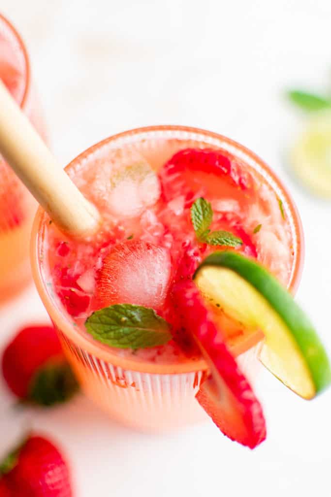 Top down view of a mojito with strawberries and lime.