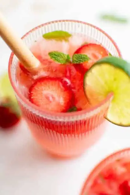 Close up view of a mojito with strawberries and lime slice.