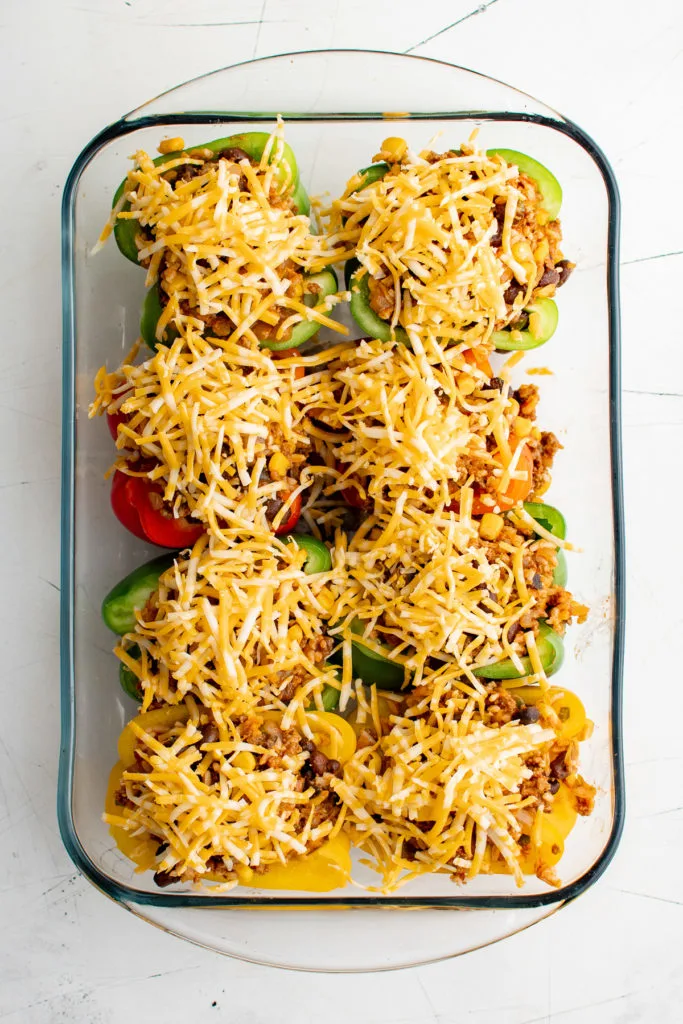 Top down view of stuffed peppers topped with shredded cheese.