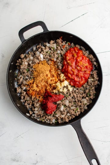 Salsa, tomato paste, garlic, and taco seasoning added to ground beef.