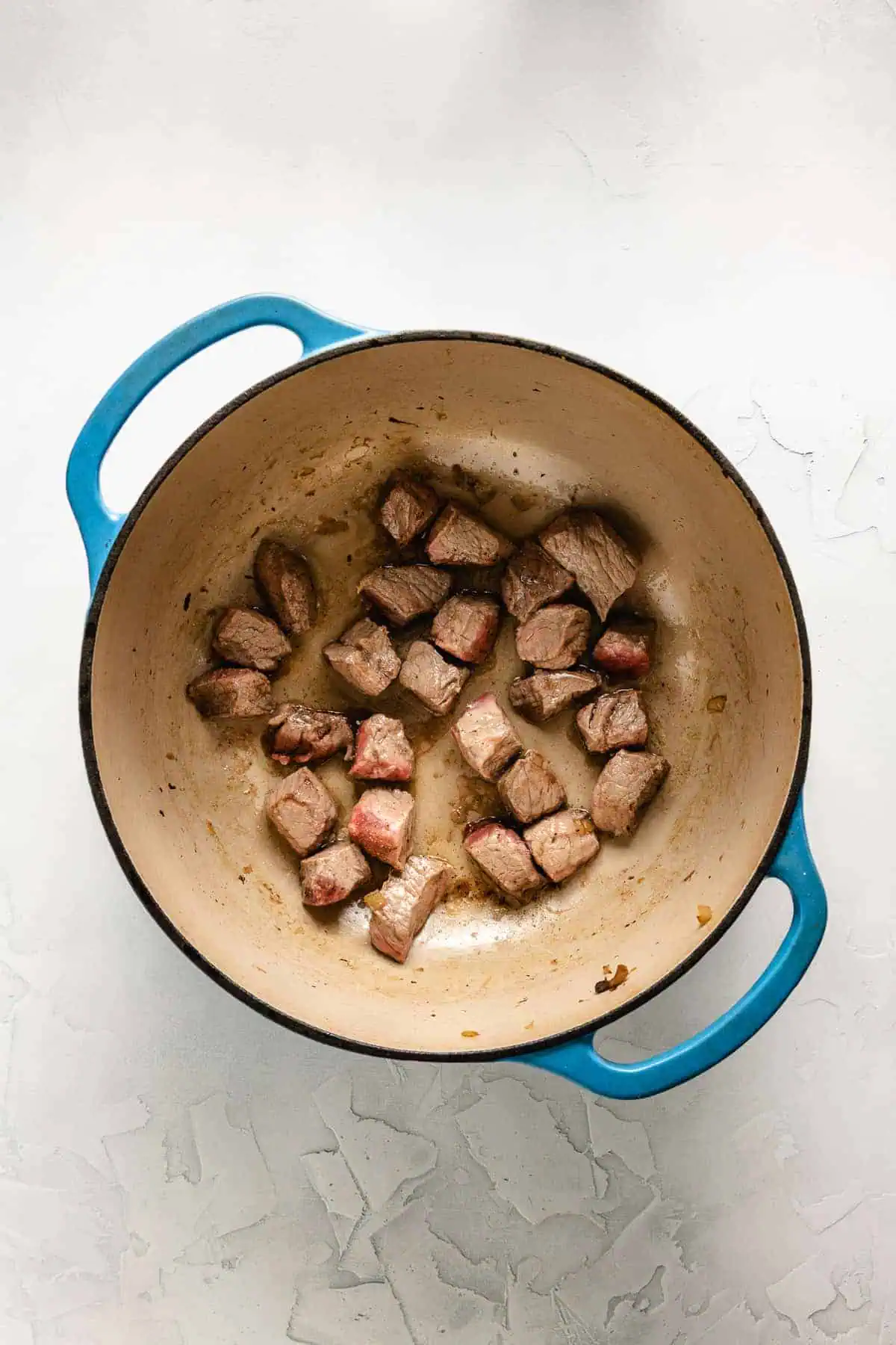 Cubed beef cooking in a pan.
