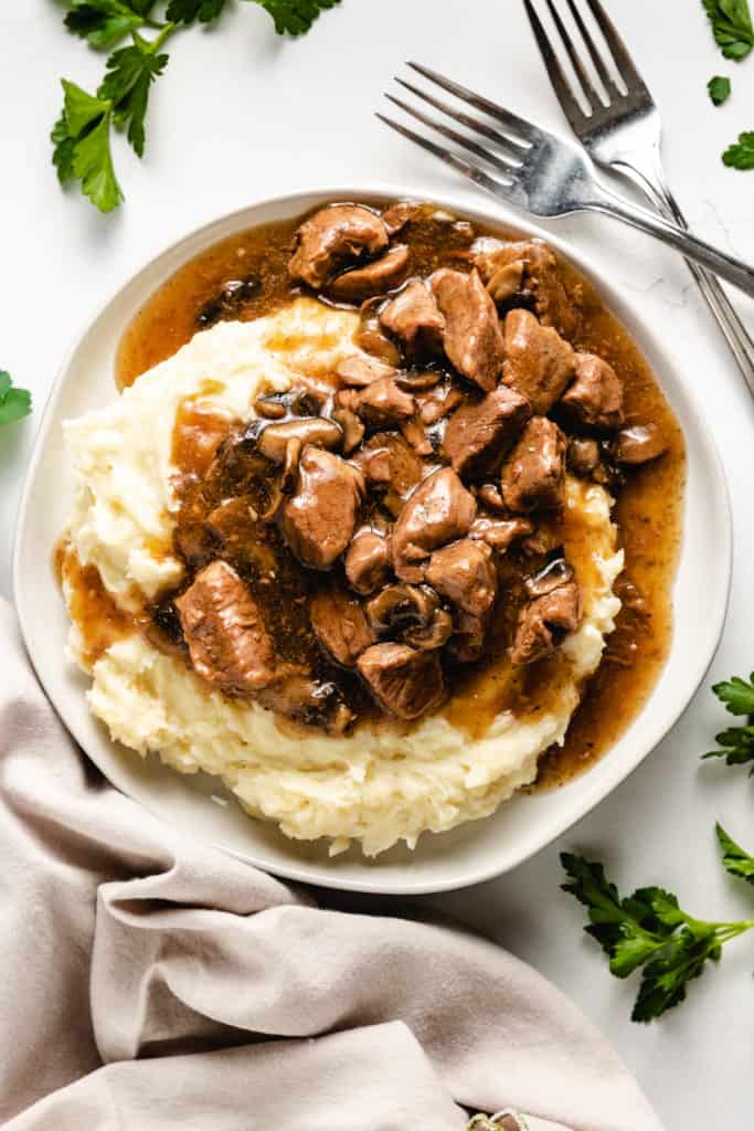 Top down view of beef tips and gravy on potatoes.