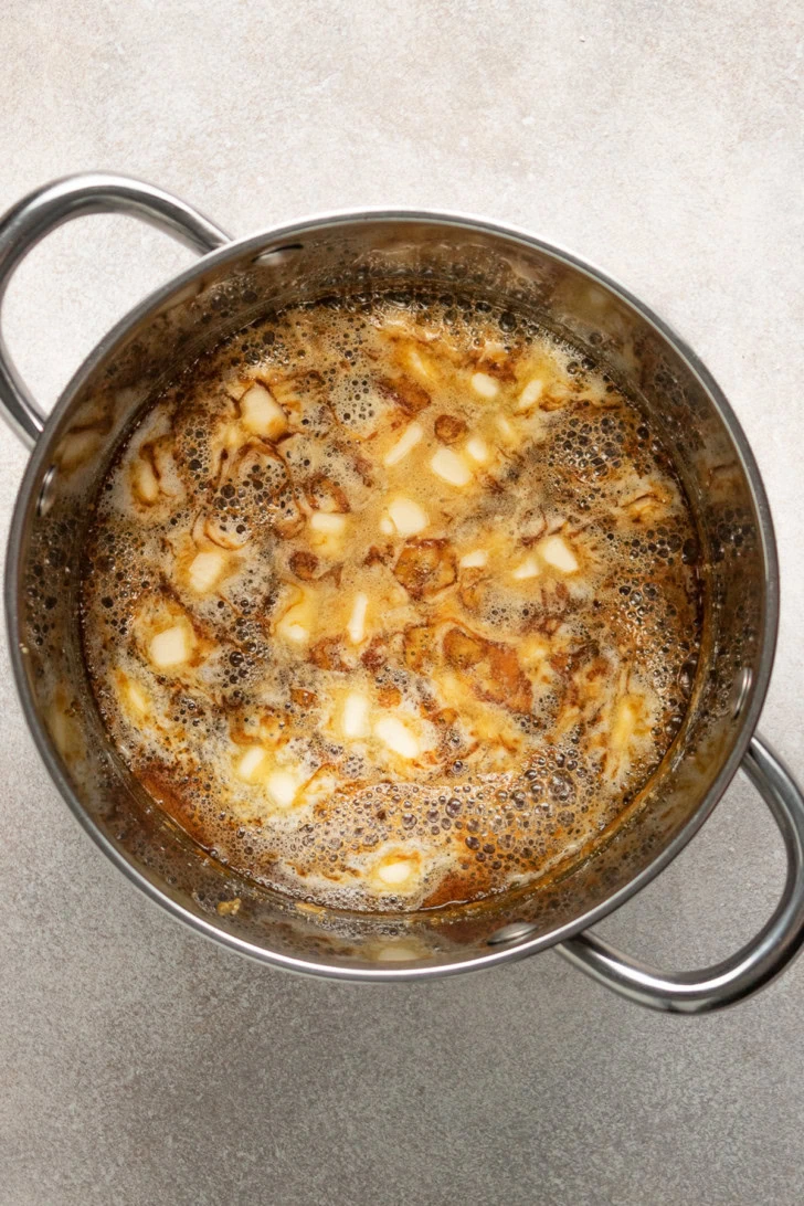 Butter cubes melting on top of sugar in a pan.