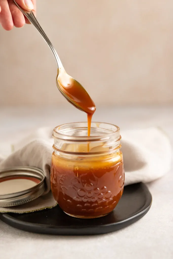 Spoon being dipped into caramel sauce.
