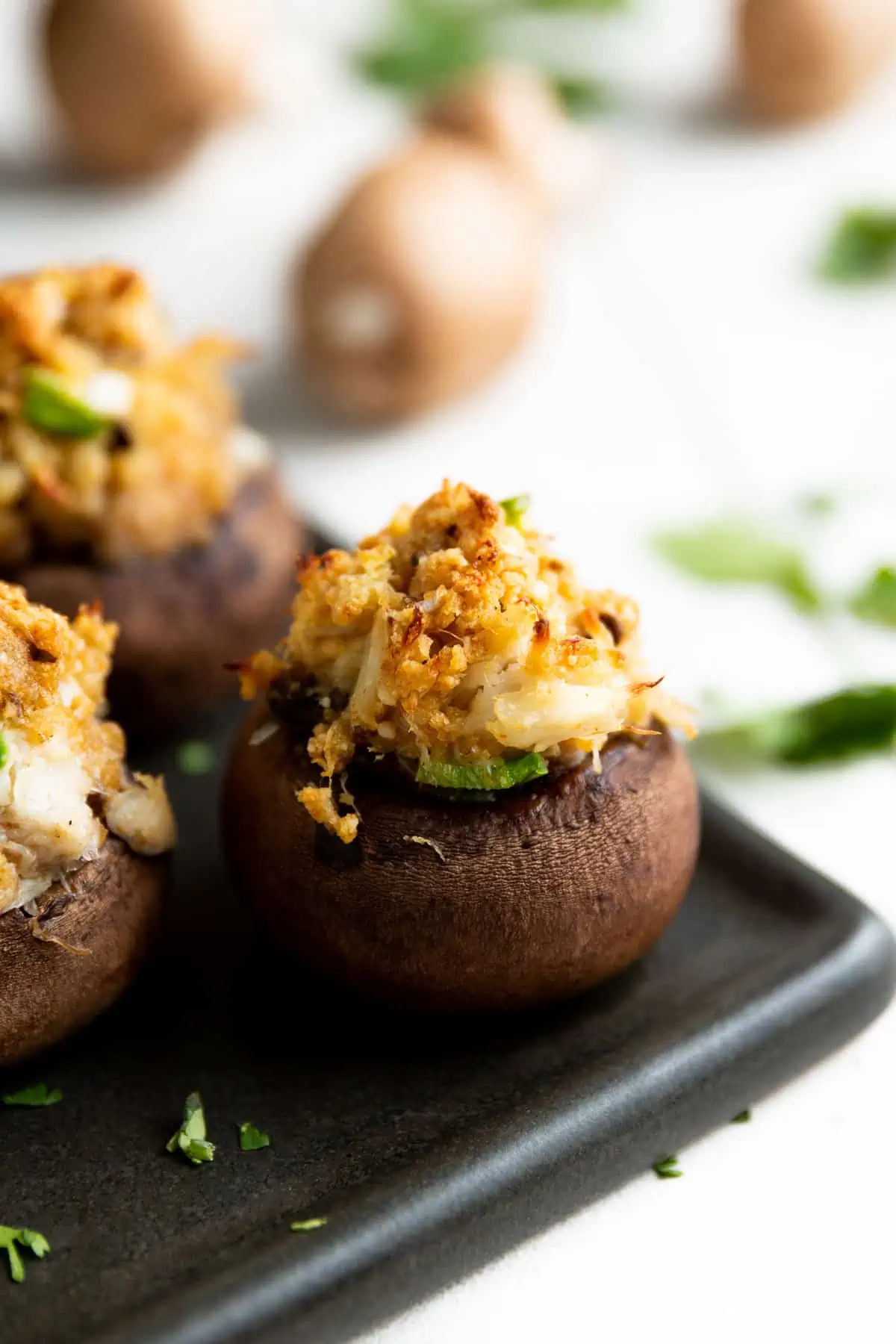 Close up of a crab stuffed mushroom on a black platter.