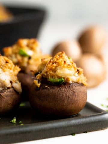 Crab stuffed mushroom in front of a cast iron pan.