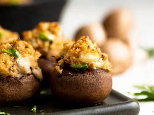 Crab stuffed mushroom in front of a cast iron pan.