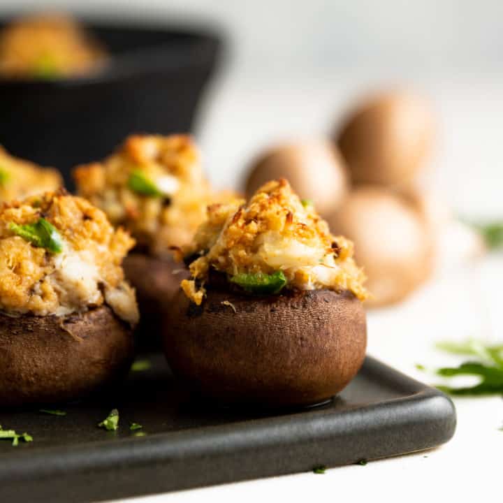 Crab stuffed mushroom in front of a cast iron pan.