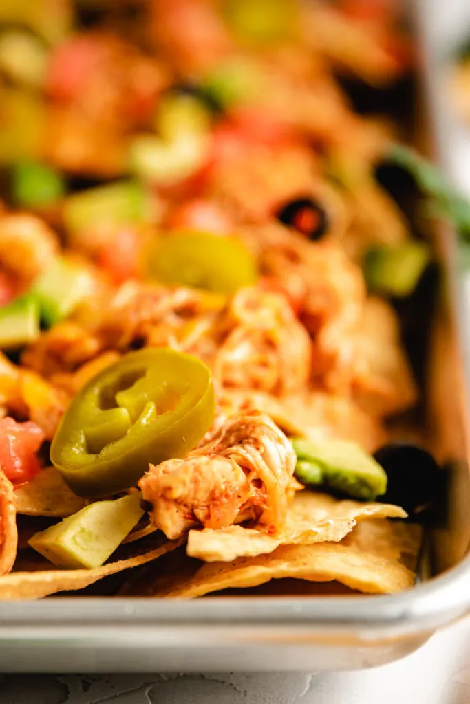 Close up view of jalapenos on chicken nachos.