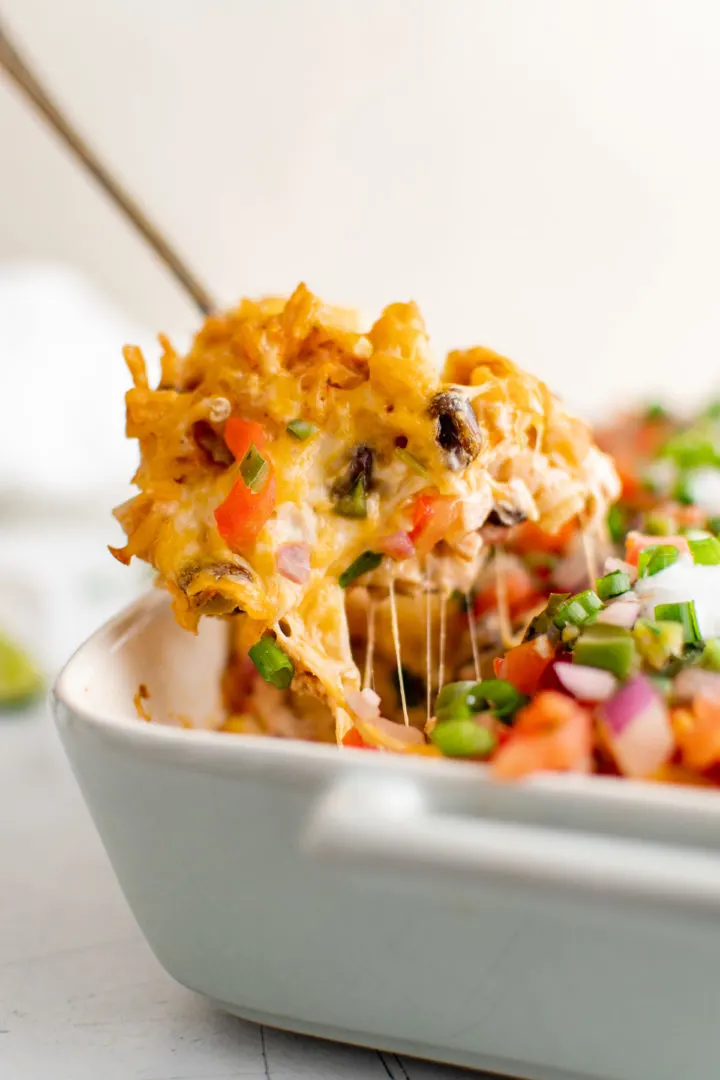Serving fiesta chicken casserole from a 9x13 baking dish.