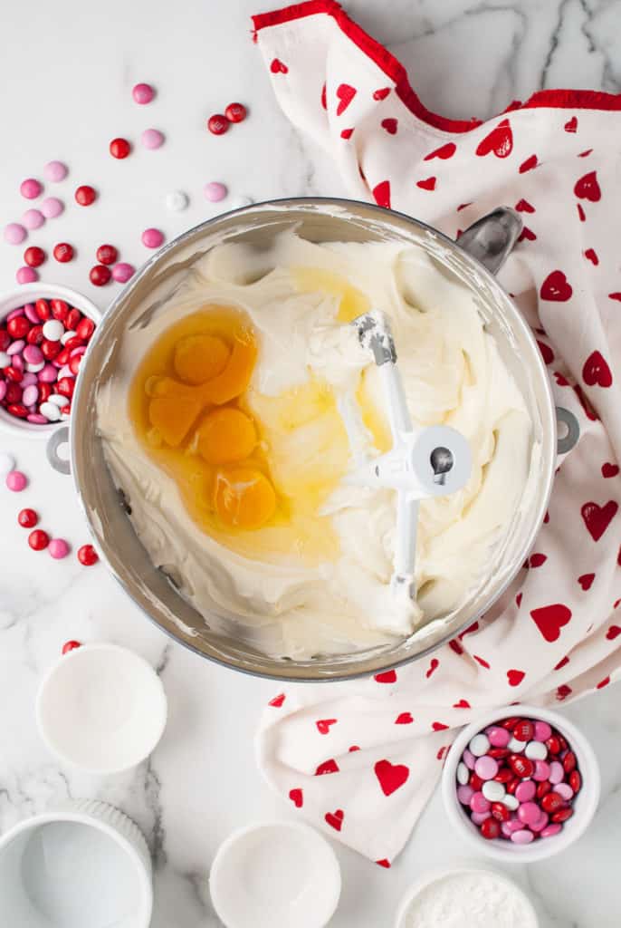 Eggs and cheesecake batter in a mixing bowl.