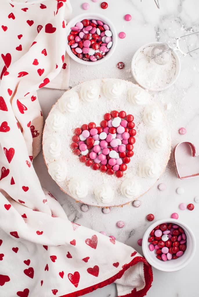 Top down view of a cheesecake with candy and whipped cream