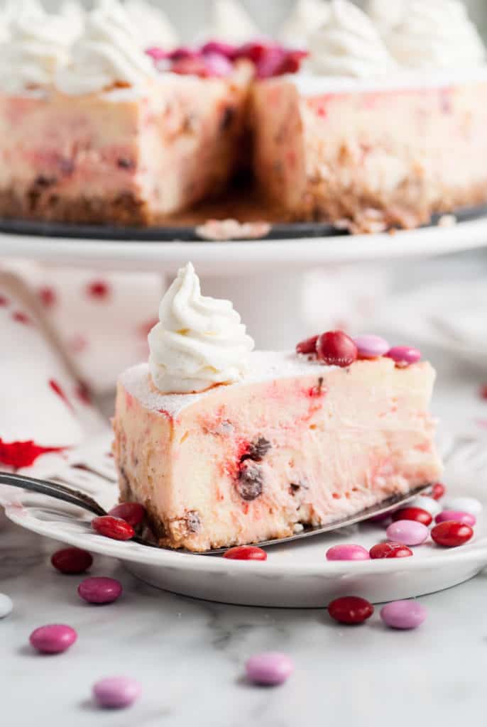 Slice of cheesecake with whipped cream on a spatula.