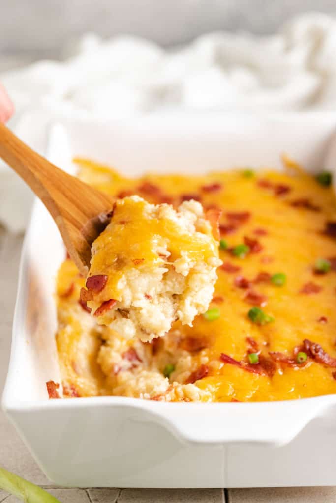 Scoop of mashed potato casserole on a wooden spoon.