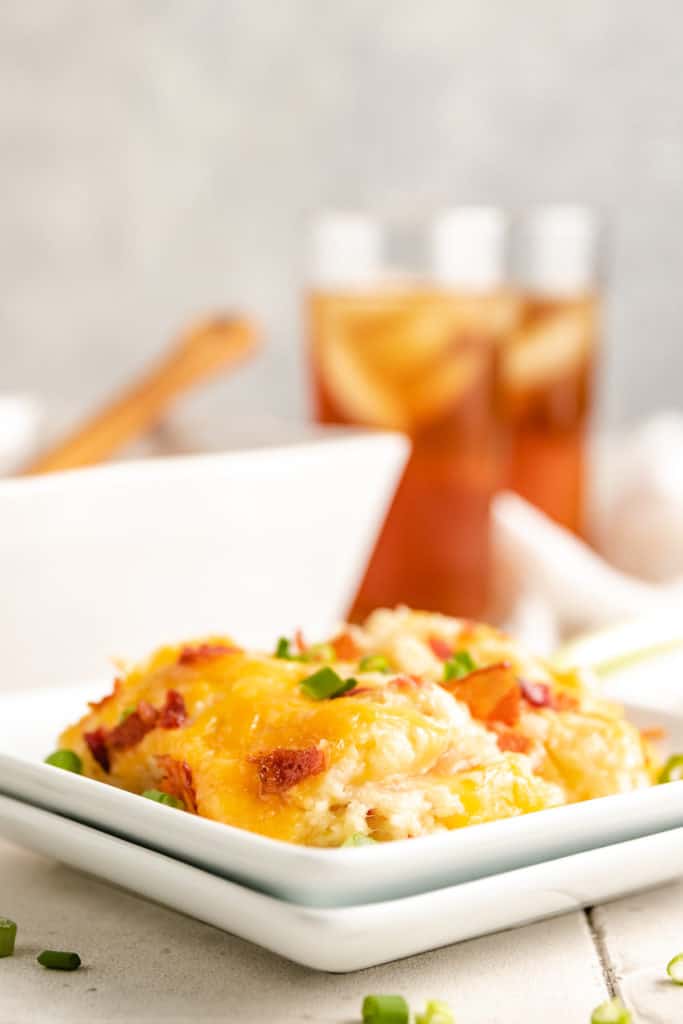 Scoop of twice baked potato casserole on a white plate.