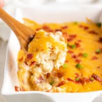 Twice baked potato casserole being scooped from a pan.
