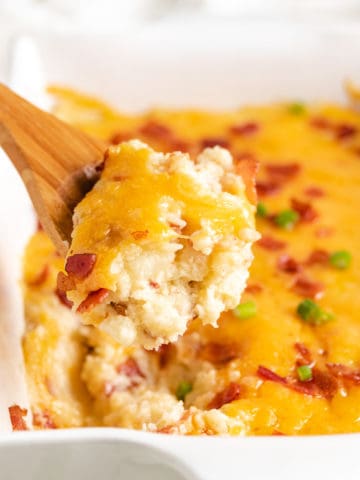 Twice baked potato casserole being scooped from a pan.