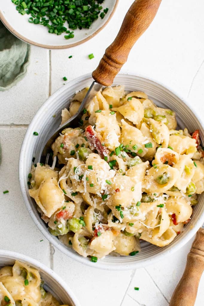 Top down view of peas and pasta mixed in a bowl.