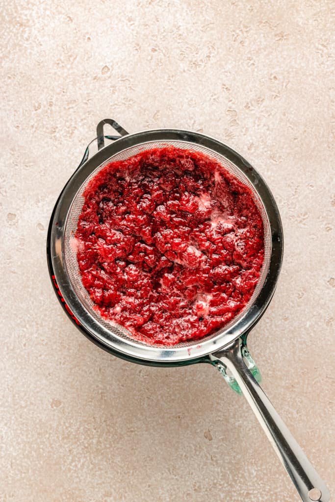 Cooked strawberries in a mesh strainer.