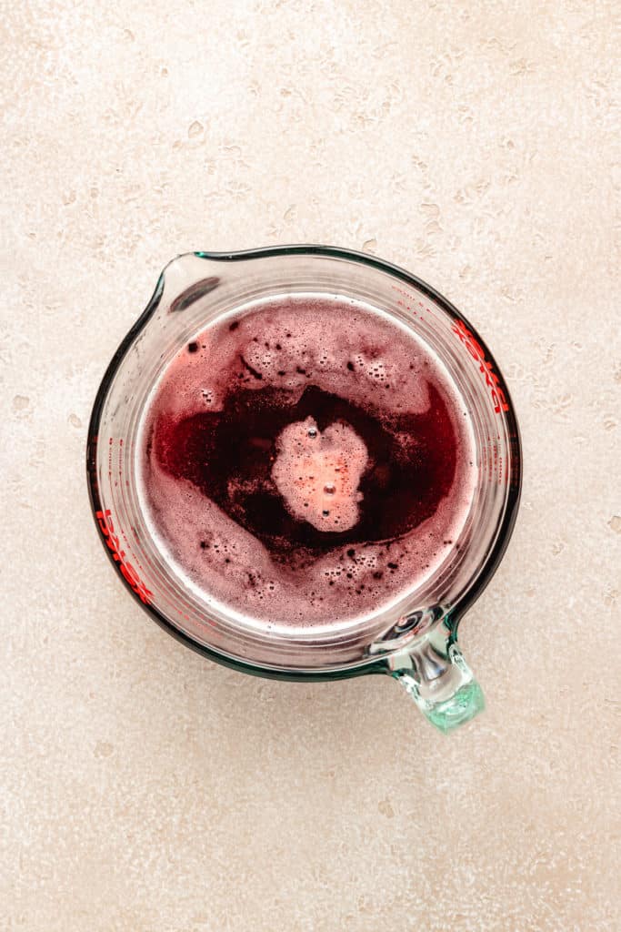 Strawberry simple syrup in a measuring cup.