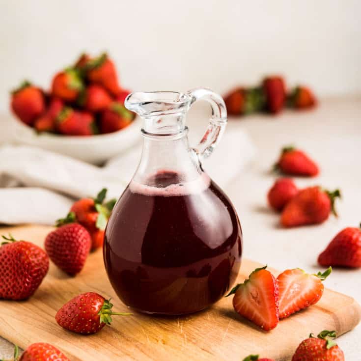Fresh strawberries around strawberry simple syrup.