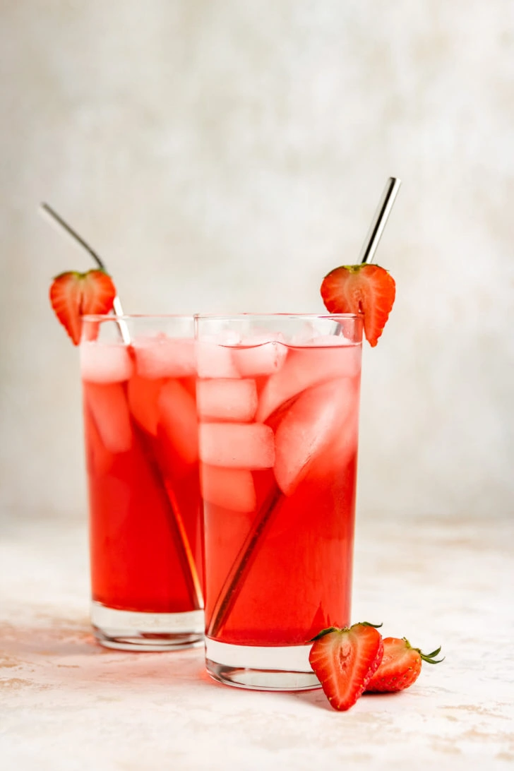 Two glasses of homemade soda with strawberries.