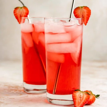 Two glasses of strawberry soda with metal straws.